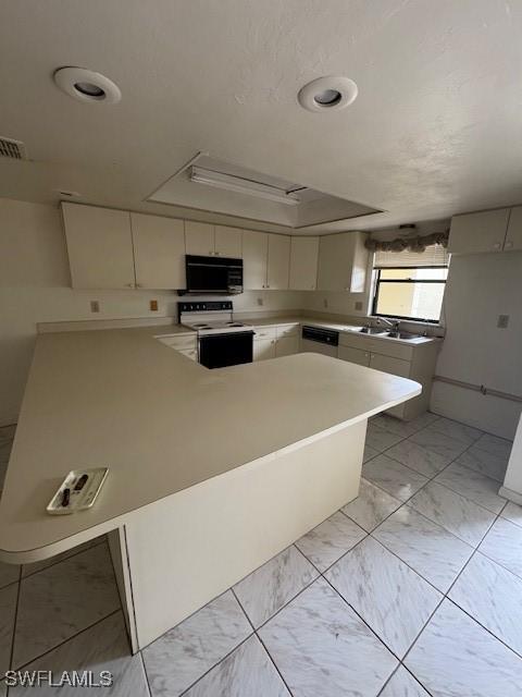 3911 Country Club Blvd Unit 102, Cape Coral, FL 33904 - kitchen with white electric range oven, black microwave, dishwasher, light countertops, and a peninsula
