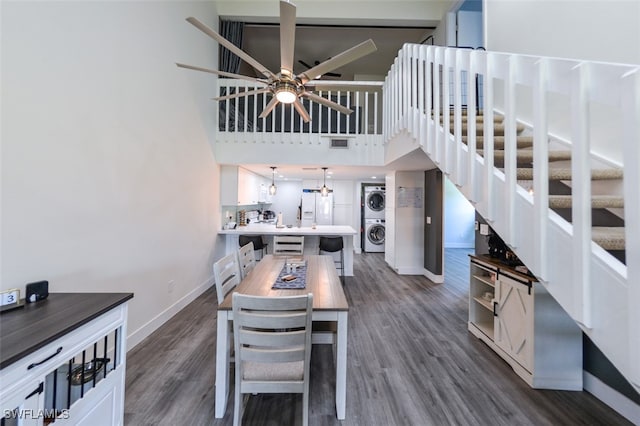 12964 Meadowood Ct, Fort Myers, FL 33919 - dining area with stacked washer / drying machine, baseboards, dark wood-style flooring, stairs, and a towering ceiling