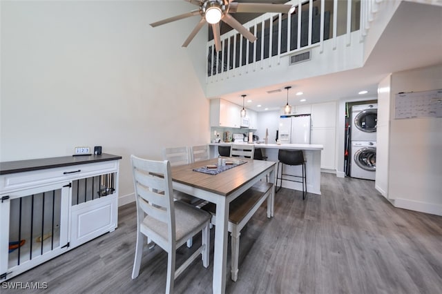 12964 Meadowood Ct, Fort Myers, FL 33919 - dining room with stacked washer and clothes dryer, wood finished floors, ceiling fan, baseboards, and a towering ceiling