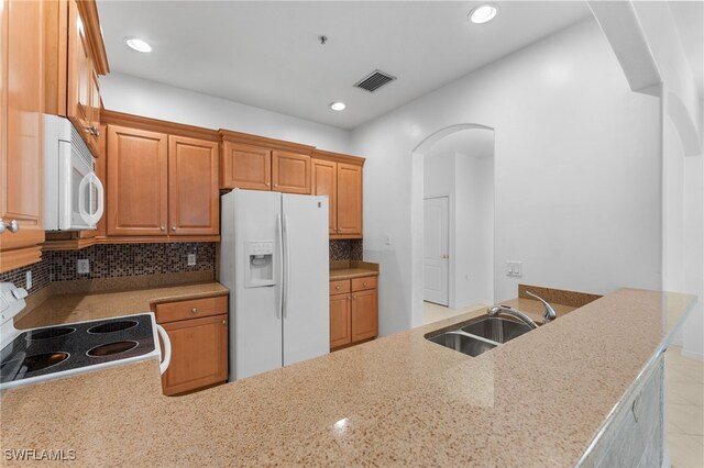 4381 Lazio Way Unit 501, Fort Myers, FL 33901 - kitchen featuring white appliances, a sink, arched walkways, tasteful backsplash, and light stone countertops