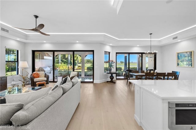 16304 Corsica Way Unit 101, Naples, FL 34110 - living area featuring a raised ceiling, ceiling fan, light wood-style flooring, a chandelier, and recessed lighting