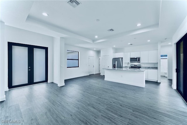 352 Rawlings Ave, Lehigh Acres, FL 33974 - unfurnished living room with a tray ceiling, recessed lighting, dark wood-style floors, french doors, and baseboards