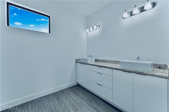352 Rawlings Ave, Lehigh Acres, FL 33974 - bathroom featuring wood finished floors, double vanity, and baseboards
