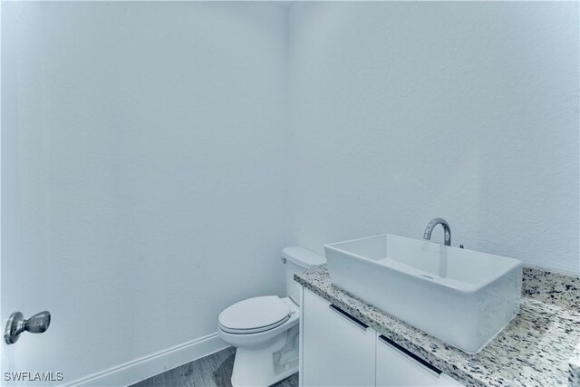 352 Rawlings Ave, Lehigh Acres, FL 33974 - half bath featuring toilet, vanity, baseboards, and wood finished floors