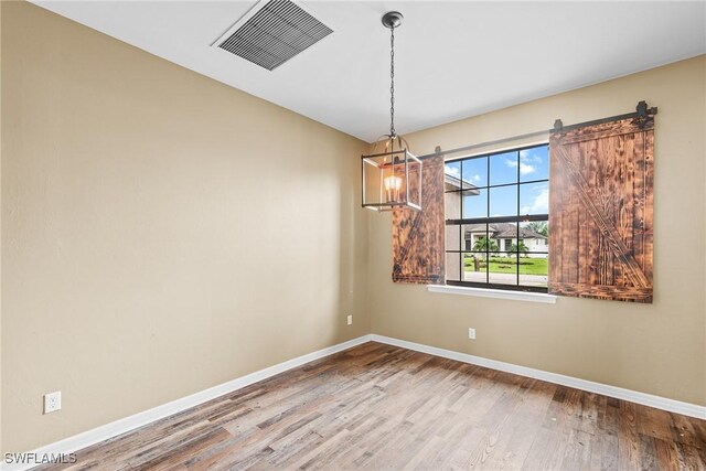 2211 SW 12th Ln, Cape Coral, FL 33991 - spare room featuring wood finished floors and a chandelier
