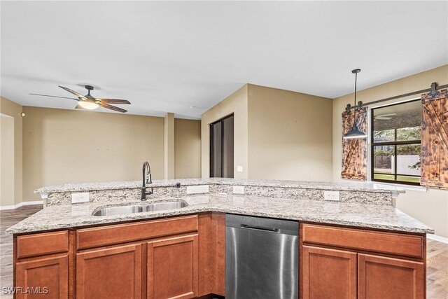 2211 SW 12th Ln, Cape Coral, FL 33991 - kitchen with stainless steel dishwasher, wood finished floors, ceiling fan, light stone counters, and brown cabinets