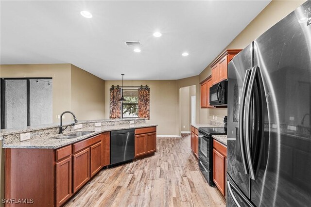 2211 SW 12th Ln, Cape Coral, FL 33991 - kitchen with black appliances, light wood-style flooring, brown cabinetry, recessed lighting, and pendant lighting