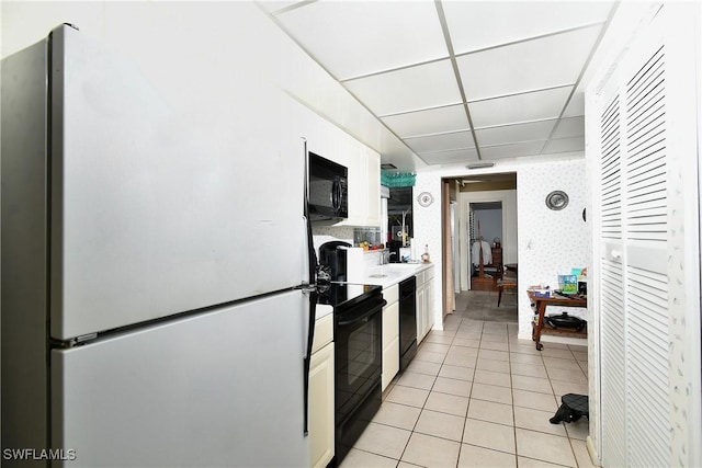 104 Waterview Ave, Lehigh Acres, FL 33936 - kitchen with black appliances, white cabinetry, light tile patterned floors, and wallpapered walls