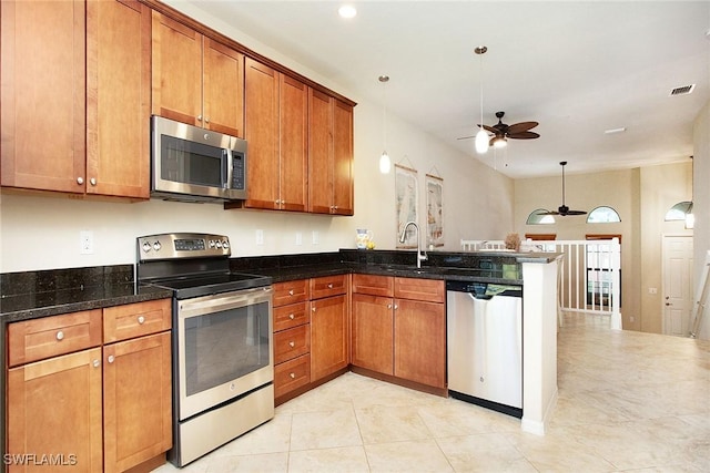 9065 Albion Ln N Unit 4909, Naples, FL 34113 - kitchen with a ceiling fan, appliances with stainless steel finishes, brown cabinetry, a peninsula, and dark stone countertops