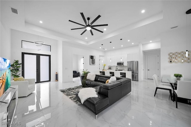 1921 SW 4th St, Cape Coral, FL 33991 - living room with a tray ceiling, light marble finish flooring, recessed lighting, a ceiling fan, and french doors
