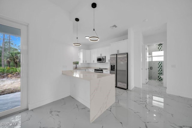 1205 W 14th St, Lehigh Acres, FL 33972 - kitchen featuring appliances with stainless steel finishes, a peninsula, light countertops, white cabinetry, and light marble finish flooring