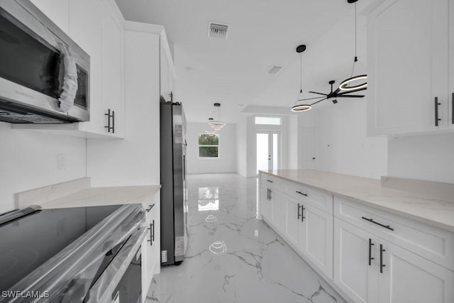 1205 W 14th St, Lehigh Acres, FL 33972 - kitchen with stainless steel appliances, light marble finish flooring, white cabinets, decorative light fixtures, and light stone counters