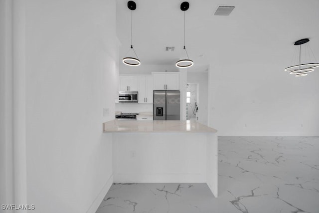 1205 W 14th St, Lehigh Acres, FL 33972 - kitchen with appliances with stainless steel finishes, marble finish flooring, white cabinetry, light countertops, and a peninsula