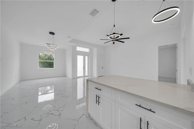 1205 W 14th St, Lehigh Acres, FL 33972 - kitchen featuring light marble finish floors, open floor plan, white cabinetry, light stone counters, and hanging light fixtures