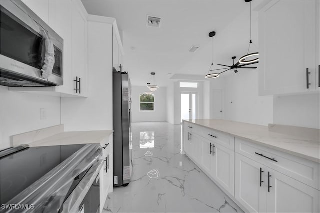 1205 W 14th St, Lehigh Acres, FL 33972 - kitchen featuring appliances with stainless steel finishes, light marble finish flooring, white cabinetry, light stone countertops, and decorative light fixtures