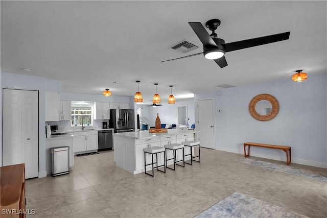 2317 El Dorado Pkwy W, Cape Coral, FL 33914 - kitchen with stainless steel appliances, a kitchen bar, a kitchen island, white cabinetry, and light countertops