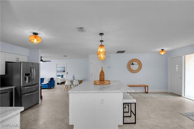 2317 El Dorado Pkwy W, Cape Coral, FL 33914 - kitchen with stainless steel fridge with ice dispenser, a breakfast bar area, white cabinetry, decorative light fixtures, and a kitchen island