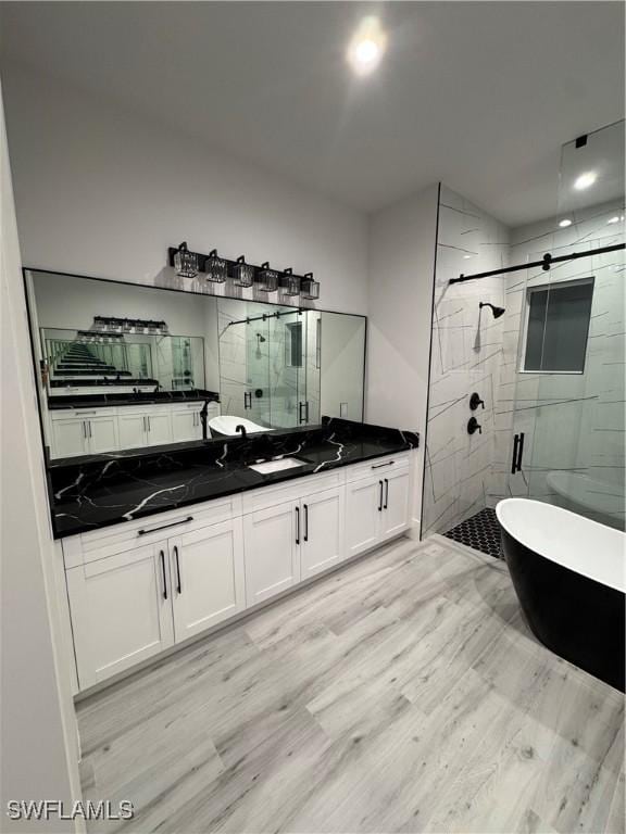 367 10th St NE, Naples, FL 34120 - full bathroom with a shower stall, double vanity, a freestanding tub, and wood finished floors
