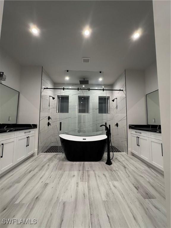 367 10th St NE, Naples, FL 34120 - full bath featuring a stall shower, two vanities, a freestanding tub, wood finished floors, and recessed lighting