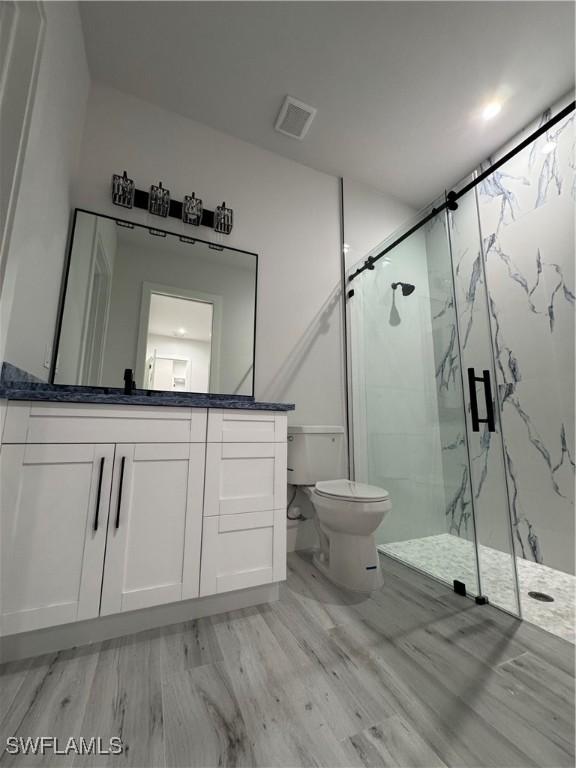 367 10th St NE, Naples, FL 34120 - bathroom featuring wood finished floors, a marble finish shower, and vanity