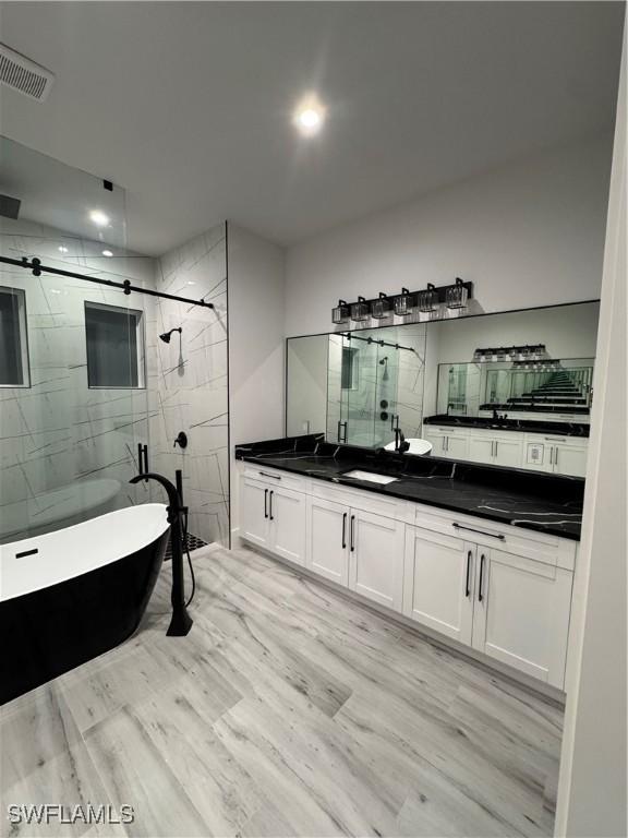 367 10th St NE, Naples, FL 34120 - full bath with a marble finish shower, double vanity, a freestanding bath, wood finished floors, and recessed lighting