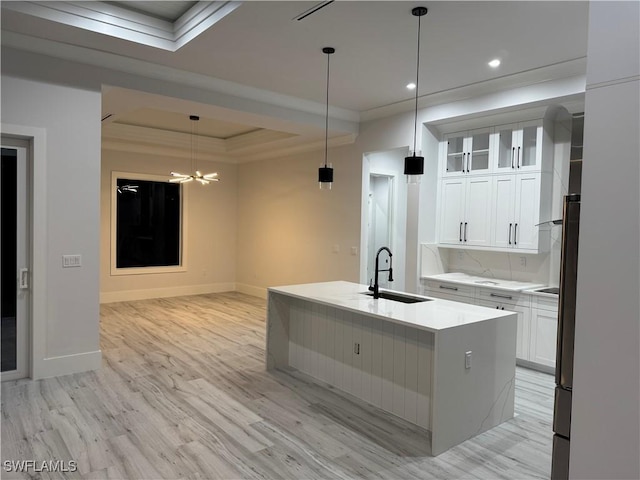 367 10th St NE, Naples, FL 34120 - kitchen featuring a tray ceiling, light wood finished floors, white cabinetry, light countertops, and crown molding