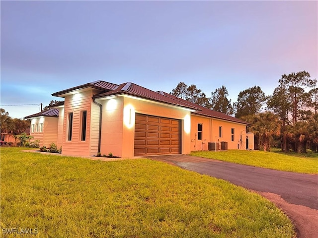 367 10th St NE, Naples, FL 34120 - view of front of house with a metal roof, an attached garage, asphalt driveway, a standing seam roof, and a front lawn