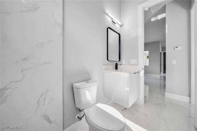 2512 10th St W, Lehigh Acres, FL 33971 - bathroom with marble tiled floors, toilet, vanity, and baseboards