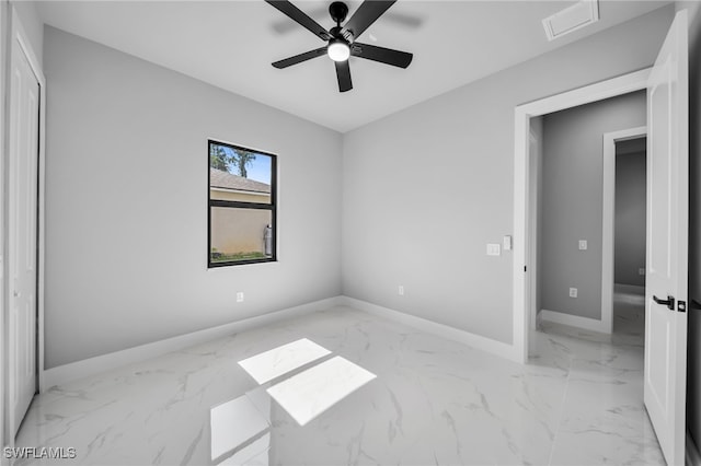 2512 10th St W, Lehigh Acres, FL 33971 - unfurnished bedroom featuring baseboards, light marble finish floors, and a ceiling fan