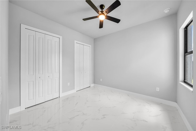 2512 10th St W, Lehigh Acres, FL 33971 - unfurnished bedroom featuring marble tiled floors, multiple closets, baseboards, and a ceiling fan