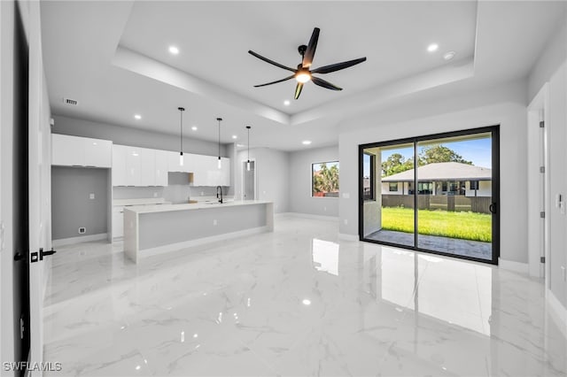 2512 10th St W, Lehigh Acres, FL 33971 - unfurnished living room featuring a tray ceiling, a sink, recessed lighting, baseboards, and light marble finish flooring