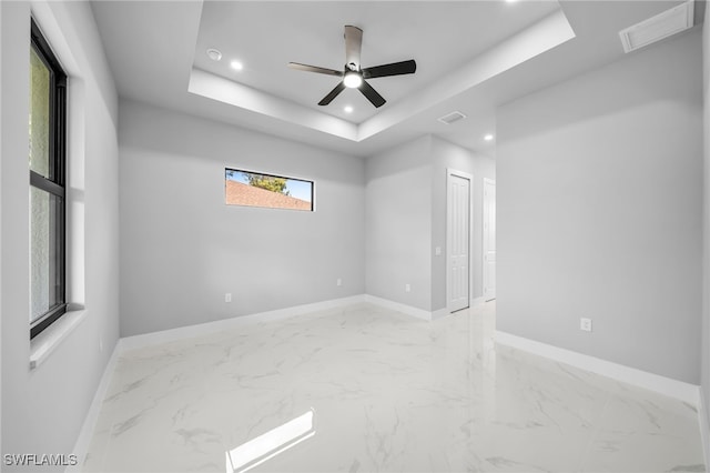 2512 10th St W, Lehigh Acres, FL 33971 - spare room featuring baseboards, marble finish flooring, a tray ceiling, and recessed lighting