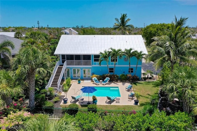 1043 Sand Castle Rd, Sanibel, FL 33957 - back of property with stairs, a patio area, a chimney, an outdoor pool, and a metal roof