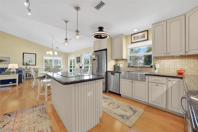1043 Sand Castle Rd, Sanibel, FL 33957 - kitchen featuring stainless steel appliances, dark countertops, light wood-style flooring, decorative backsplash, and lofted ceiling