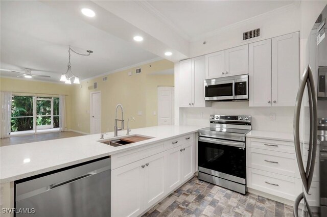 1089 Winding Pines Cir Unit 106, Cape Coral, FL 33909 - kitchen featuring appliances with stainless steel finishes, ornamental molding, a peninsula, white cabinetry, and light countertops