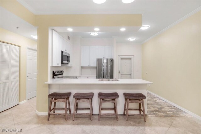 1089 Winding Pines Cir Unit 106, Cape Coral, FL 33909 - kitchen featuring appliances with stainless steel finishes, a peninsula, white cabinets, a breakfast bar area, and ornamental molding