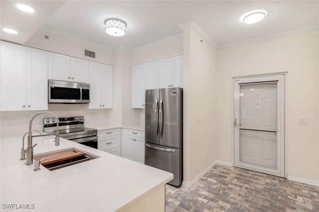 1089 Winding Pines Cir Unit 106, Cape Coral, FL 33909 - kitchen with appliances with stainless steel finishes, light countertops, white cabinets, crown molding, and brick flooring