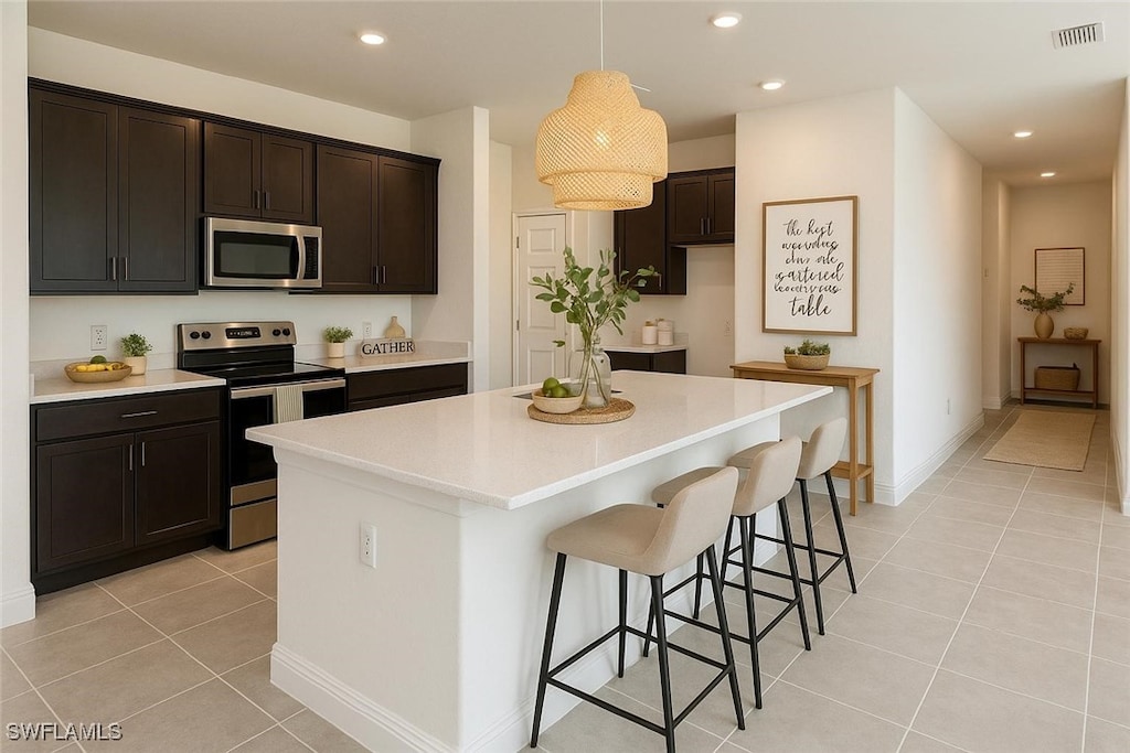 2331 NW 28th Ave, Cape Coral, FL 33993 - kitchen with stainless steel appliances, light tile patterned floors, a kitchen island, recessed lighting, and light countertops