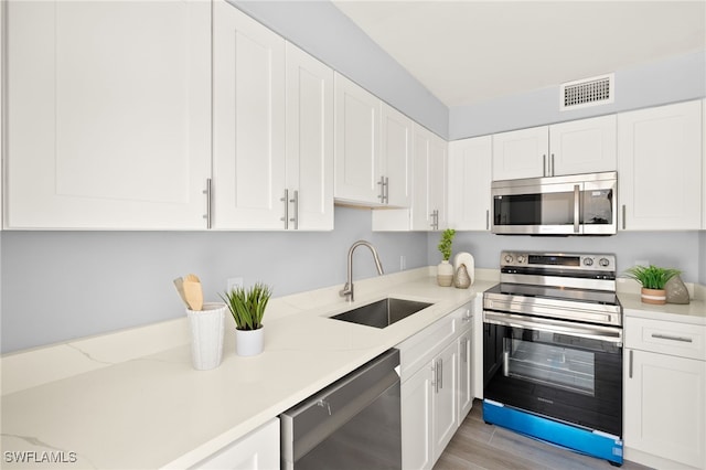 548 Broad Ave S Unit 548, Naples, FL 34102 - kitchen featuring appliances with stainless steel finishes, a sink, white cabinets, and light wood-style floors