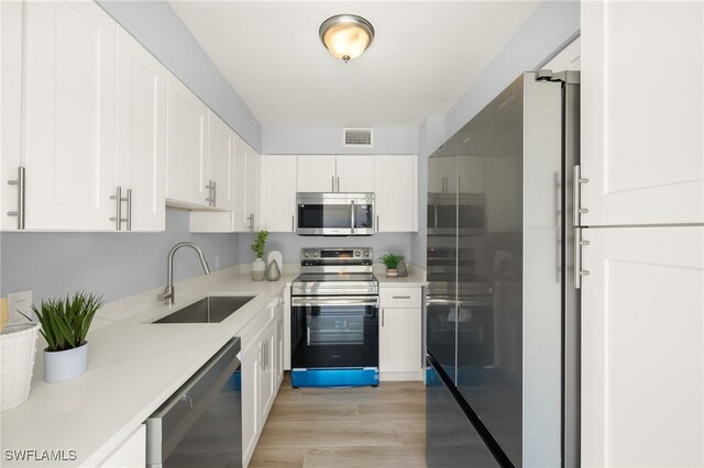 548 Broad Ave S Unit 548, Naples, FL 34102 - kitchen with stainless steel appliances, a sink, light wood finished floors, white cabinets, and light countertops