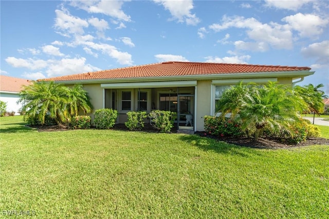 3130 Scarlet Oak Pl, North Fort Myers, FL 33903 - rear view of house with a tiled roof, stucco siding, a lawn, and a sunroom