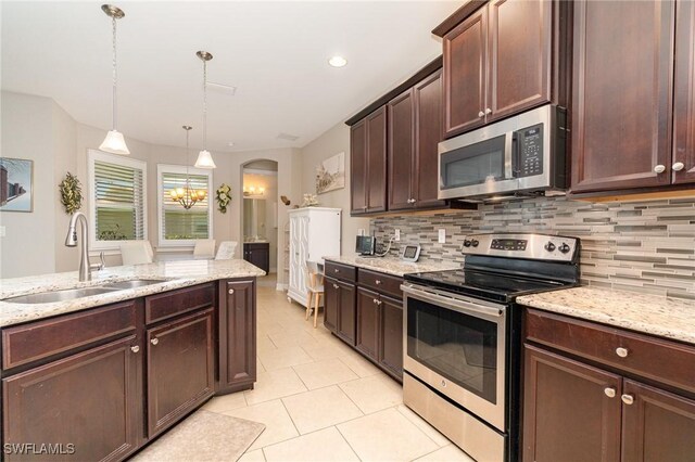 3130 Scarlet Oak Pl, North Fort Myers, FL 33903 - kitchen featuring appliances with stainless steel finishes, backsplash, dark brown cabinets, pendant lighting, and light stone counters