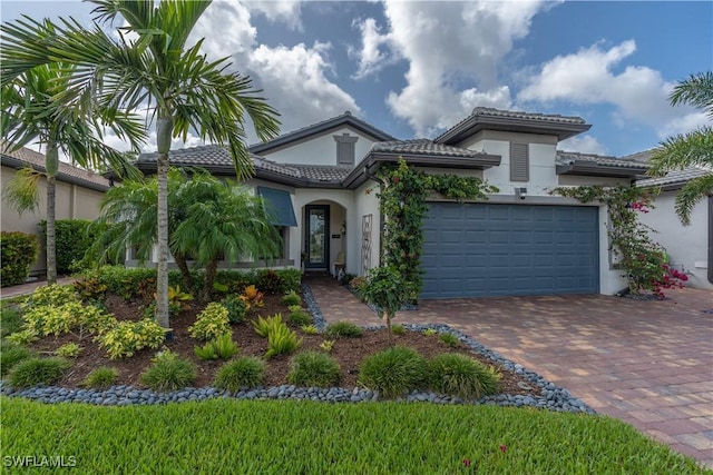 6848 Winding Cypress Dr, Naples, FL 34114 - view of front of property with stucco siding, decorative driveway, an attached garage, and a tile roof