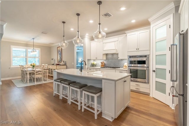6848 Winding Cypress Dr, Naples, FL 34114 - kitchen with stainless steel appliances, crown molding, backsplash, light countertops, and white cabinetry