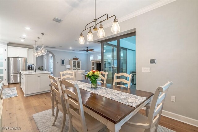 6848 Winding Cypress Dr, Naples, FL 34114 - dining space with ceiling fan, light wood-style flooring, arched walkways, crown molding, and recessed lighting