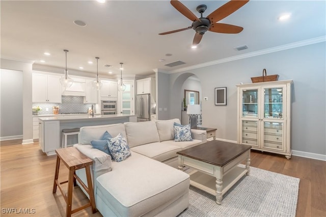 6848 Winding Cypress Dr, Naples, FL 34114 - living room with arched walkways, a ceiling fan, light wood-style flooring, ornamental molding, and recessed lighting
