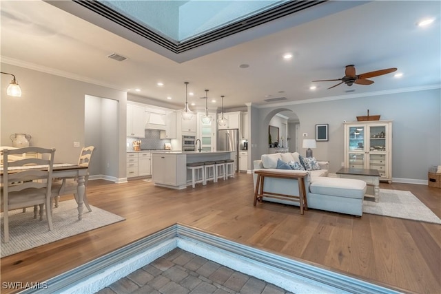 6848 Winding Cypress Dr, Naples, FL 34114 - living area featuring arched walkways, ornamental molding, a ceiling fan, recessed lighting, and wood finished floors