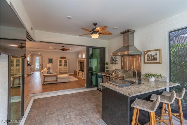 6848 Winding Cypress Dr, Naples, FL 34114 - kitchen featuring extractor fan, a ceiling fan, a peninsula, arched walkways, and light stone countertops