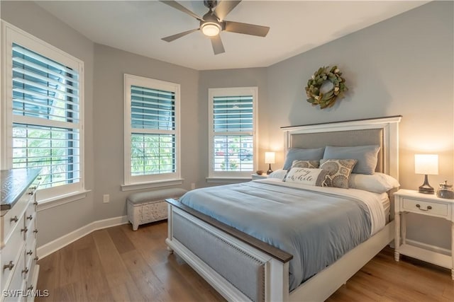 6848 Winding Cypress Dr, Naples, FL 34114 - bedroom with wood finished floors, multiple windows, baseboards, and ceiling fan