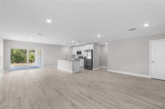 365 Woodburn Dr, Lehigh Acres, FL 33972 - unfurnished living room with recessed lighting, baseboards, light wood-type flooring, and a sink